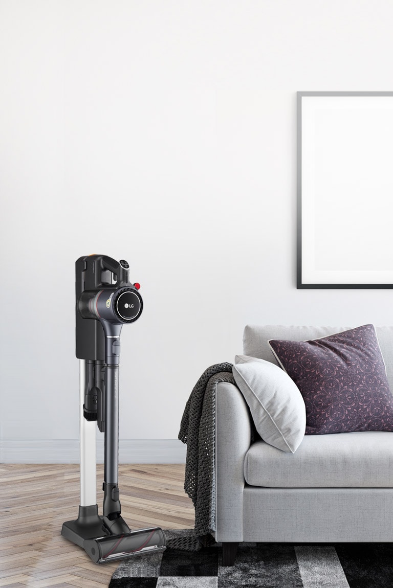 The CordZero A9 Kompressor Vacuum is in the charging stand in a bedroom next to a bed.