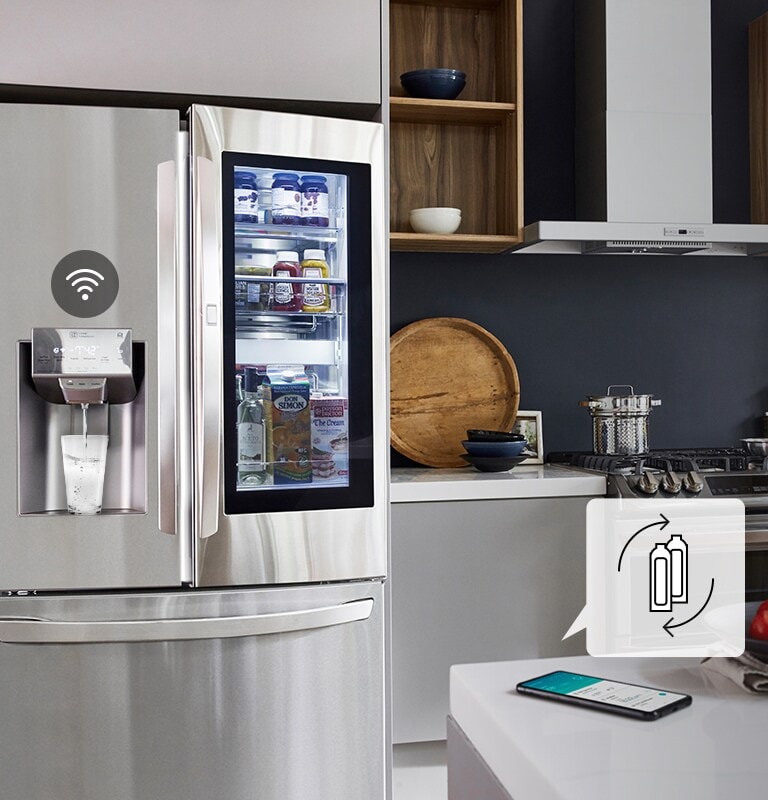 A play/pause icon is on the bottom of the screen above three dots. The second dot is highlighted indicating this is the second of three videos in a carousel. A video opens with the LG refrigerator in a kitchen. Water begins to fall into a glass from the door of the machine. The water stops flowing and the Wifi icon pops up above the water dispenser. An icon pops up above the phone that's sitting on a counter. The icon shows two bottles and arrows circling indicating the consumables need to be replaced. 