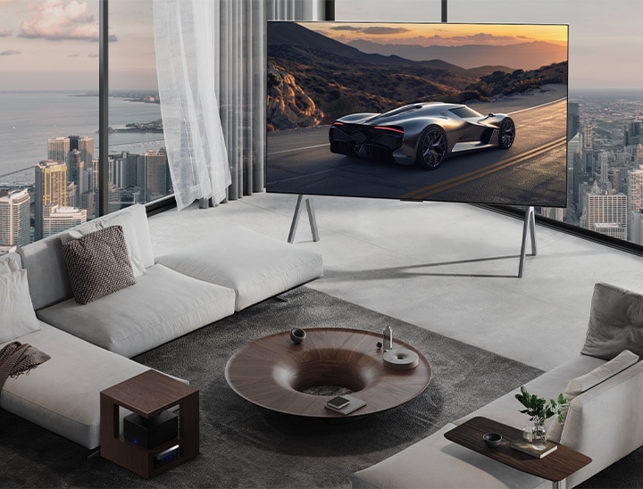 Spacious living room with a view of a cityscape. LG OLED TV is on a stand. The Ultra Slim Design makes the screen feel immersive.  Zero Connect Box is visible, but concealed. 	