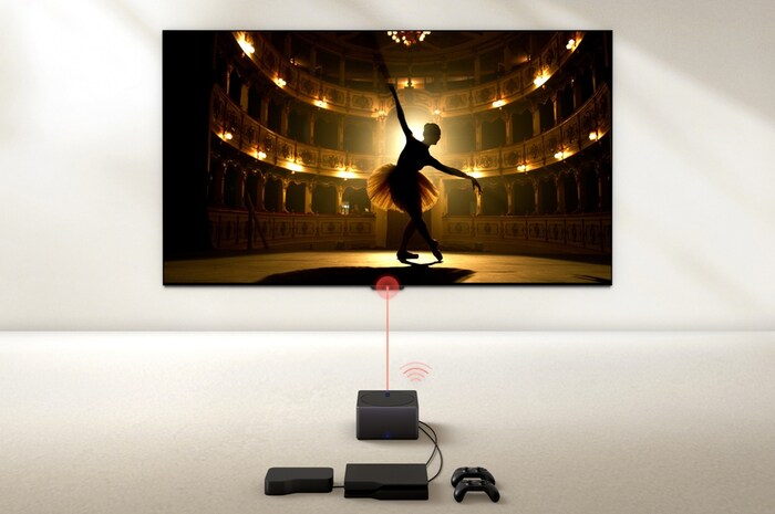 A Zero Connect Box in front of an LG OLED evo M4, and a red Wi-Fi signal and red beam emitting towards the TV. The TV displays a ballerina dancing solo on stage.