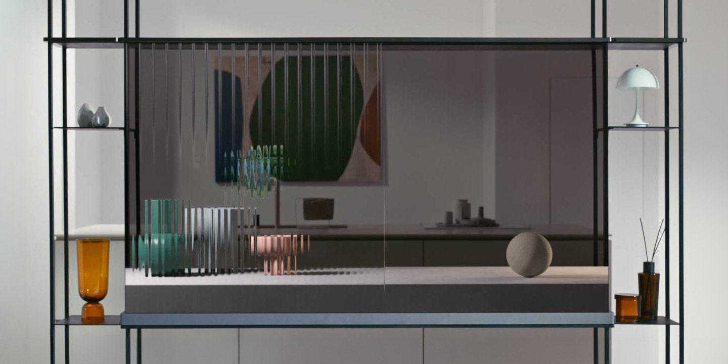 LG SIGNATURE OLED T shows a cat jumping across the transparent screen as it shows the interior space behind simultaneously. Objects are placed to the right and left attachment of the modular shelf. Another transparent TV is placed against the window framing the winter scenery outside the house. On the screen are falling flower petals. Coming back to the LG SIGNATURE OLED T in the first scene, the screen now shows three pottery objects going from blurred lines to the solidified object.