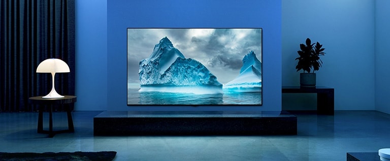 The video shows a close-up of iceberg image and there is a visual effect of blue circuit running on iceberg image. Scene changes to show a TV hanging on living room with blue lighting and background. There is a vast iceberg on TV screen.