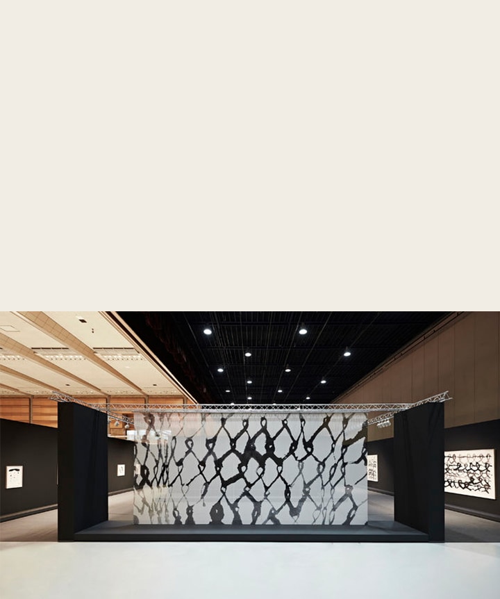 Átlátszó panelen megjelenő műalkotás kiállítási környezetben.