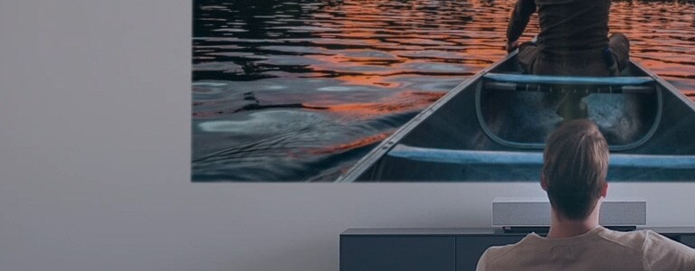 Egy férfi filmet néz az LG CineBeam nagy és éles képével