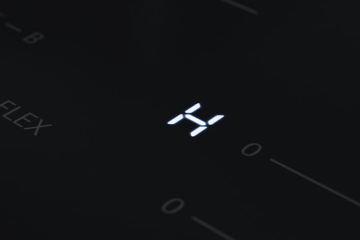 Közeli kép az LG indukciós főzőlap nagy „H” maradékhő-jelző LED-jéről.