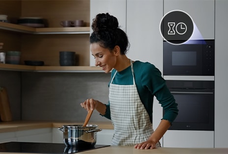 Nő kényelmesen főz a konyhában. Háttérben az LG beépíthető mikrohullámú sütő, melyen az időzítő kinagyítva van megjelenítve.