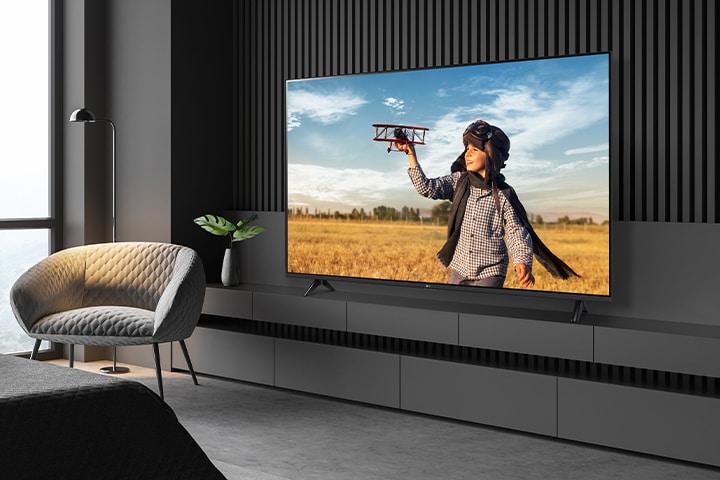 A TV a hotelszobában, egy falhoz közeli állványra van felszerelve, világos és tiszta képernyővel.