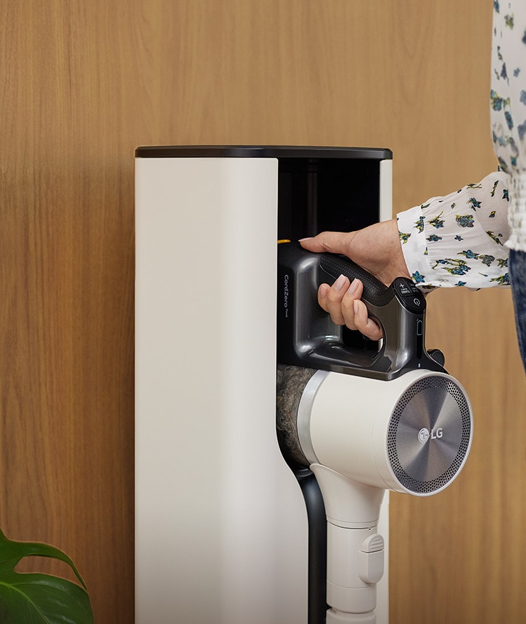 Egy nő elhelyezi az LG CordZero™ porszívót a dokkolóba.