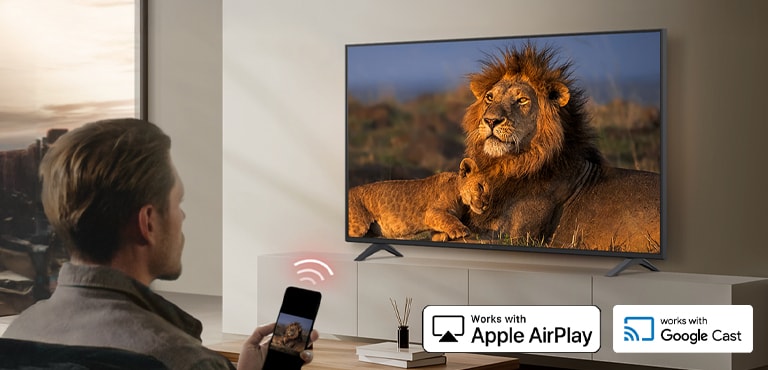 Seorang tamu hotel sedang mentransmisikan konten dari smartphone ke TV dalam kamar menggunakan teknologi transmisi nirkabel seperti AirPlay dan Google Cast.