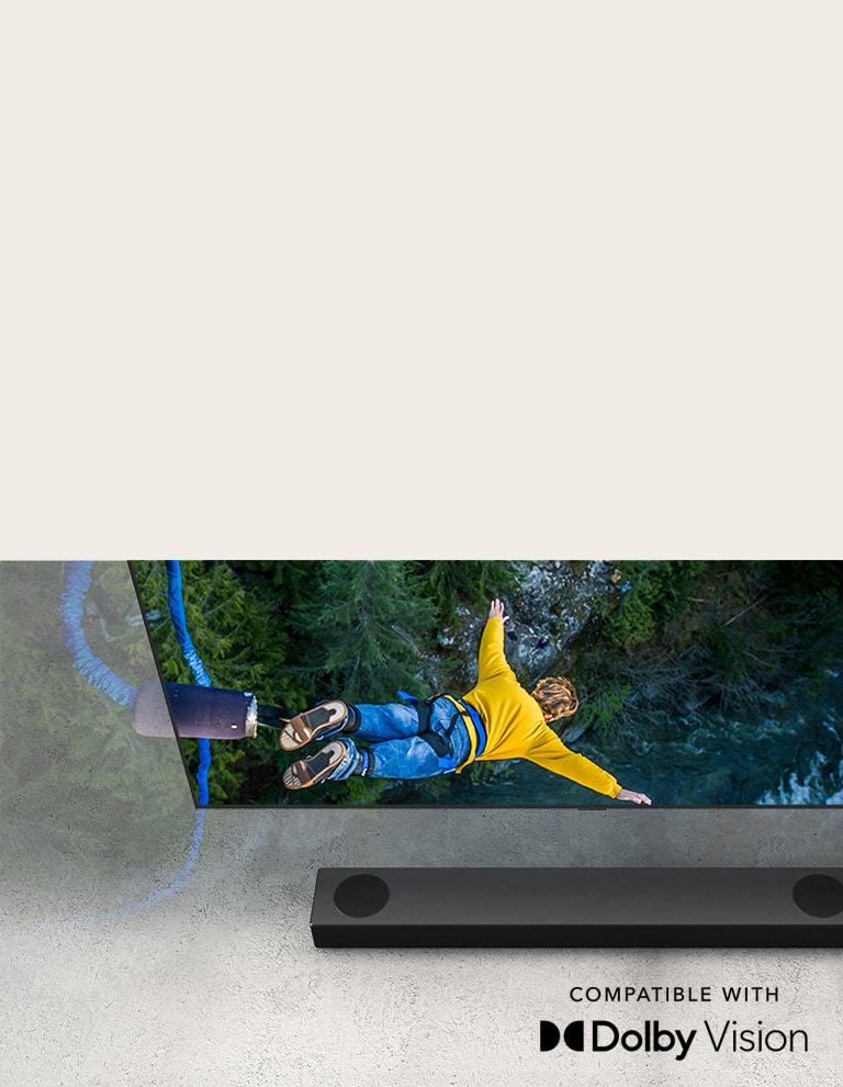TV LG menampilkan seseorang yang sedang melakukan bungee jumping, dan LG Sound Bar ditempatkan di bawah TV