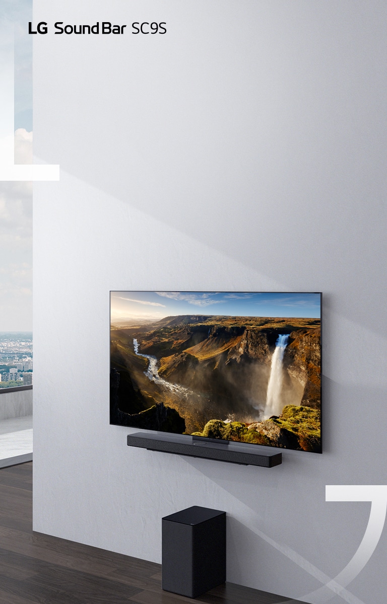 TV dan LG Sound Bar SC9S digantung di dinding putih. Di bawah subwoofer nirkabel hitam ditempatkan di lantai.
