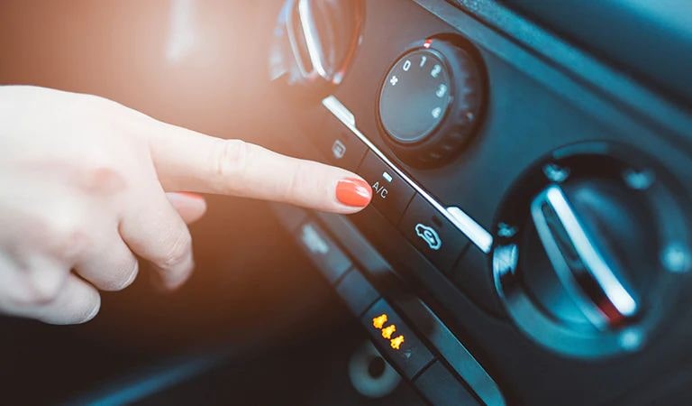 A person turning on the airconditioner button in a car.