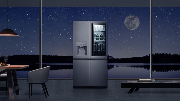 LG SIGNATURE Kulkas diletakkan tepat di tengah rumah dengan lanskap terang bulan di luar jendela.