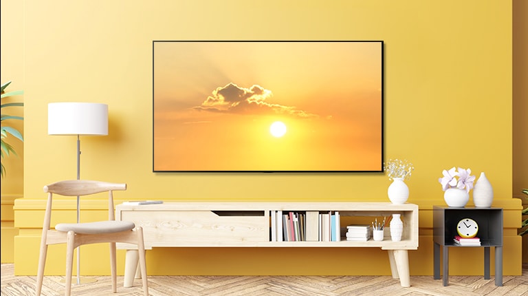 Sebuah TV di ruang tamu sedang menayangkan burung terbang di langit berwarna kuning dan adegan transisi untuk menampilkan TV yang ditempatkan di kamar tidur yang menayangkan saluran yang sama. 