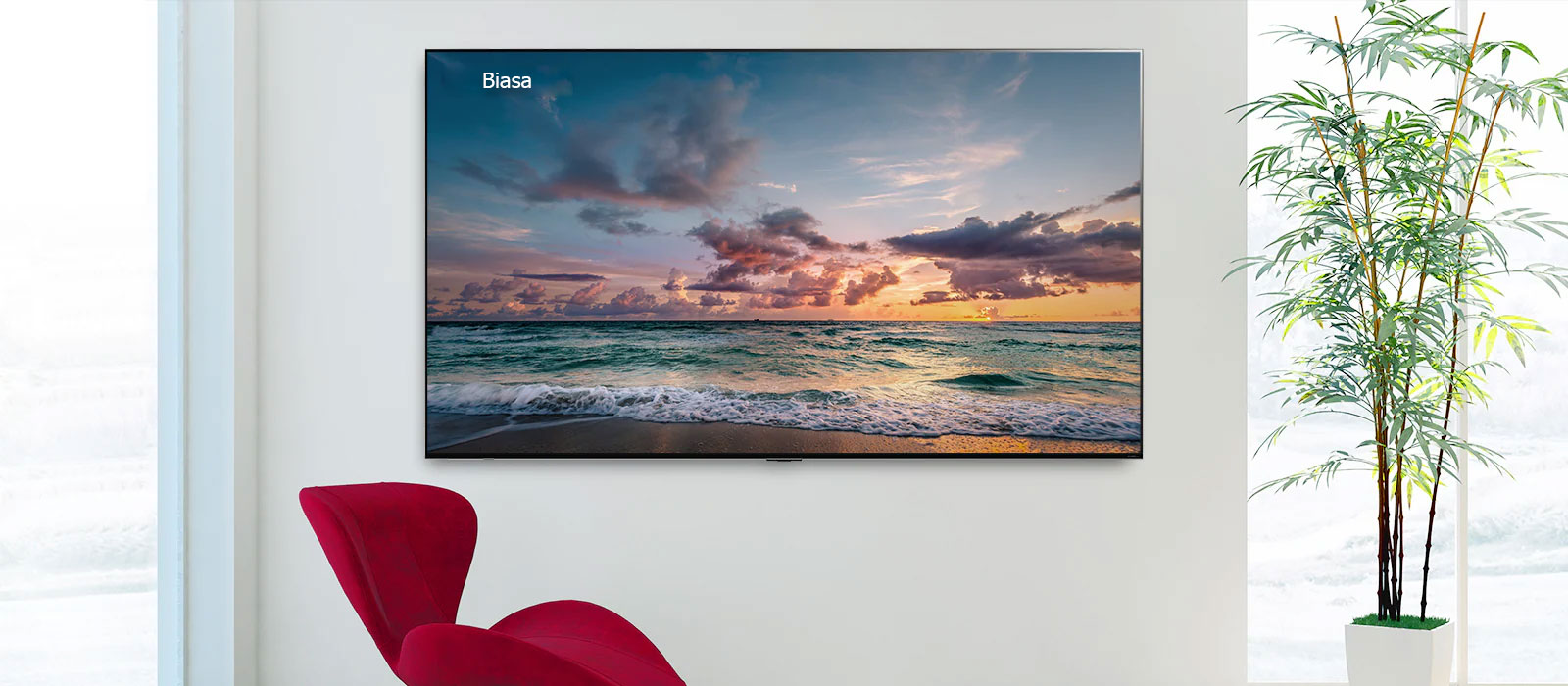 TV layar lebar terpasang di dinding dengan kursi warna merah di depan. Layarnya menayangkan ombak yang memecah dengan lembut di pantai. Menggulir dari kiri ke kanan menunjukkan perbedaan warna antara LCD TV biasa dan LG QNED MiniLED.