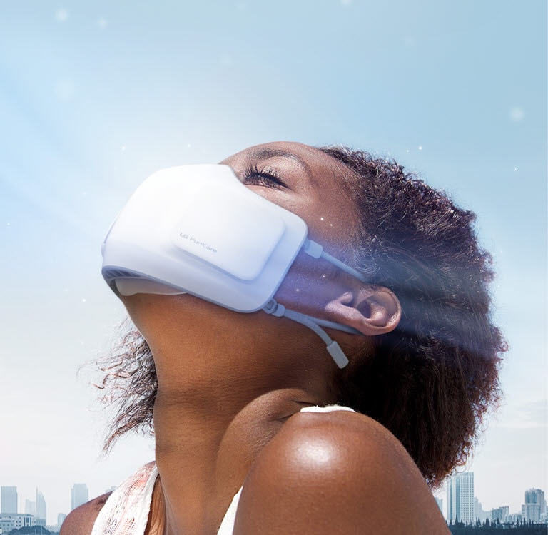 Seorang gadis mendongakkan kepala sedang menggunakan PuriCare Wearable Air Purifier terlihat dari samping. Terdapat latar belakang kota dan angin dengan debu halus beterbangan di sekitarnya. 