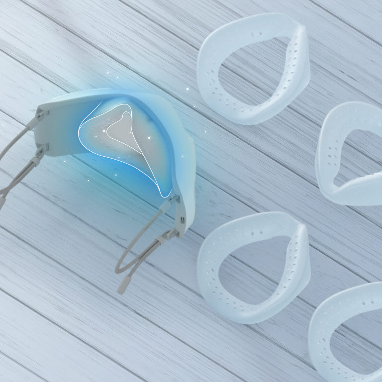 Tampak atas dan sebagian interior LG PuriCare Wearable Air Purifier dengan inner cover dan bantalan silikon tersebar di sekitarnya terletak pada sebuah meja. Tempat untuk memasang penutup silikon pada bagian dalam LG PuriCare WAP ditunjukkan dalam warna biru.