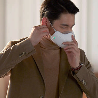 Seorang pria memasangkan LG PuriCare Wearable Air Purifier pada bagian wajahnya. 
