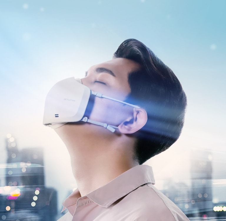 Seoarang Asia mendongakkan kepala menggunakan PuriCare Wearable Air Purifier terlihat dari samping. Terdapat pemandangan kota pada latar belakang dan angin dengan sentuhan halus