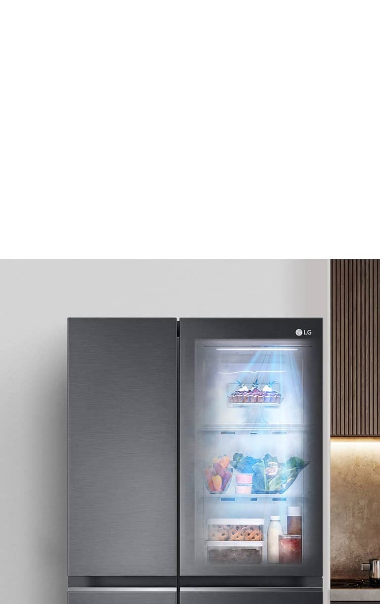 Kulkas LG dengan pintu kaca transparan menampilkan rak penuh sayuran, buah, dan susu di dapur modern.