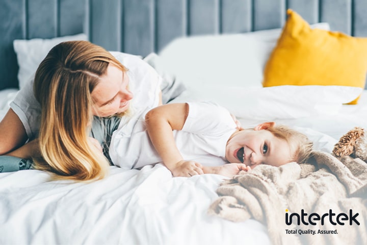 Seorang perempuan dan seorang anak berbaring di kasur sambil tersenyum
