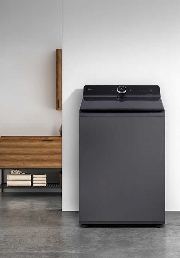 Mesin cuci top-load LG warna abu-abu gelap dengan desain ramping dan modern, ditempatkan di ruang laundry minimalis.