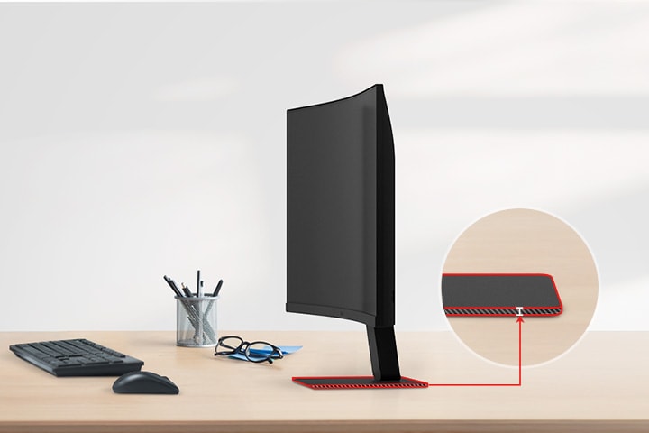 Sebuah monitor UHD dengan dudukan ramping berada diatas meja, dengan sebuah tempat pensil, gelas, keyboard dan mouse di sebelahnya