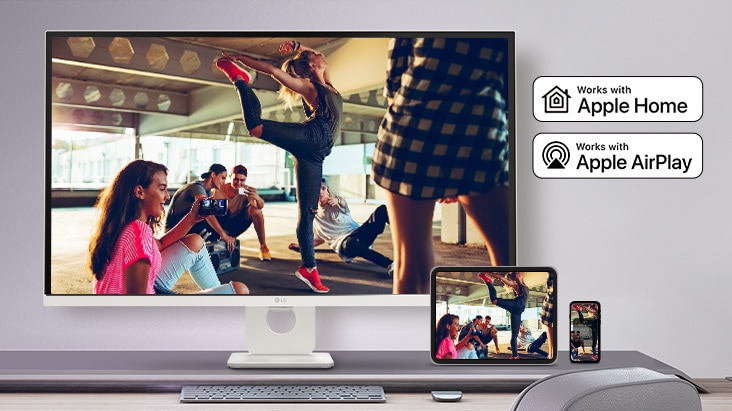 Di atas meja, terdapat monitor yang menampilkan sebuah adegan film, dan di adegan yang sama ditampilkan di tablet dan perangkat seluler yang ditempatkan di kanan bawah.