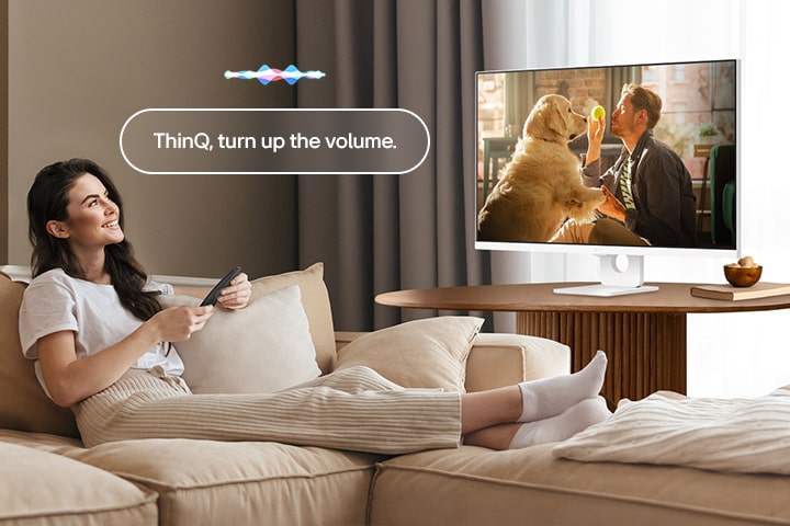 Seorang wanita sedang menaikkan volume LG Smart Monitor menggunakan Remote Kontrol Ajaib.