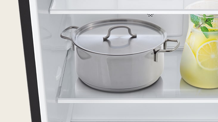 Dalam gambar, sebuah panci besar dan botol kaca yang tampak sangat berat ditaruh di rak kaca tempered di kulkas.