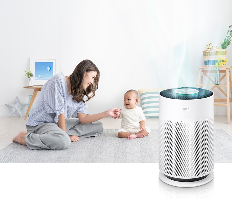 LG PuriCare-360-HIT Mom and baby are having a good time in the living room. Clean air is coming out of the air purifier on the right.