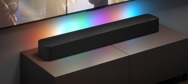 3 TV screens are shown: A woman singing with a mic in her hand, a reporter spaeaking with a mic and a tablet in her each hand and a medieval soldier in armor riding a horse. Below the TVs SF1A soundbar is placed with EQ graphics on it. On the bottom 3 icons are presented: MUSIC, VOICE and CINEMA.