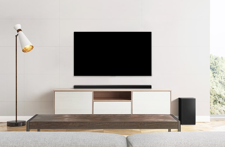 A TV, soundbar, and subwoofer placed in a plain living room.