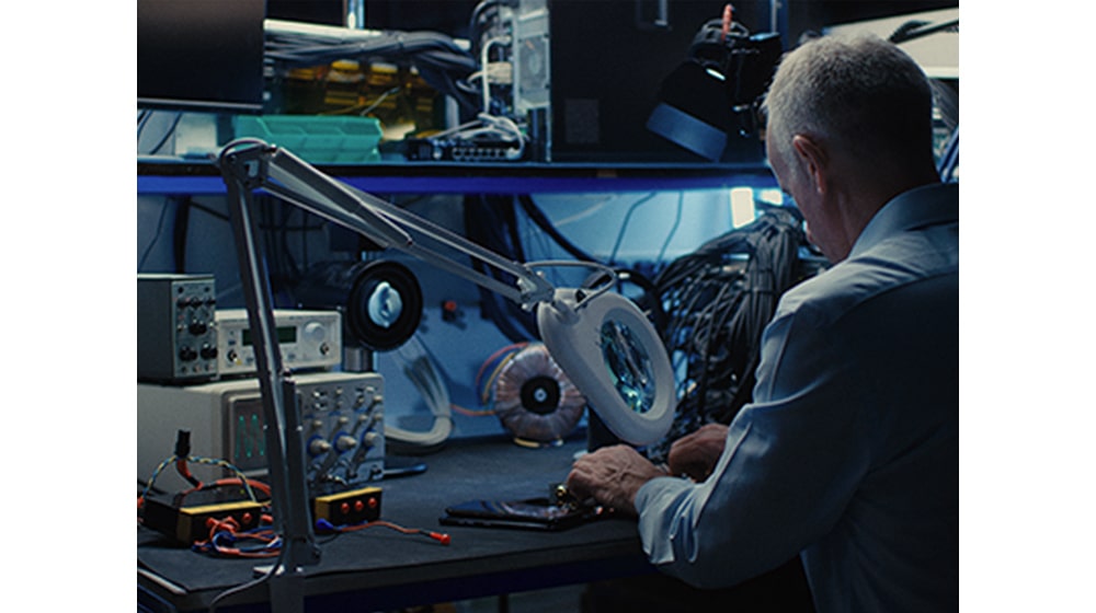 LG TONE-TF7Q A man working on professional machines at his desk.