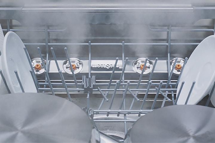 Footage of close-up view of various kinds of dishes being steam-washed inside dishwasher.