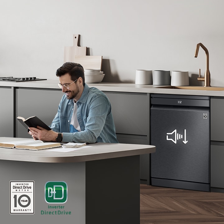 A man reading a book near an operation dishwasher, with the Inverter DirectDrive and 10-year Warranty marks displayed