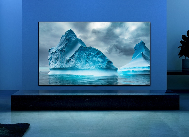 The video shows a close-up of iceberg image and there is a visual effect of blue circuit running on iceberg image. Scene changes to show a TV hanging on living room with blue lighting and background. There is a vast iceberg on TV screen.