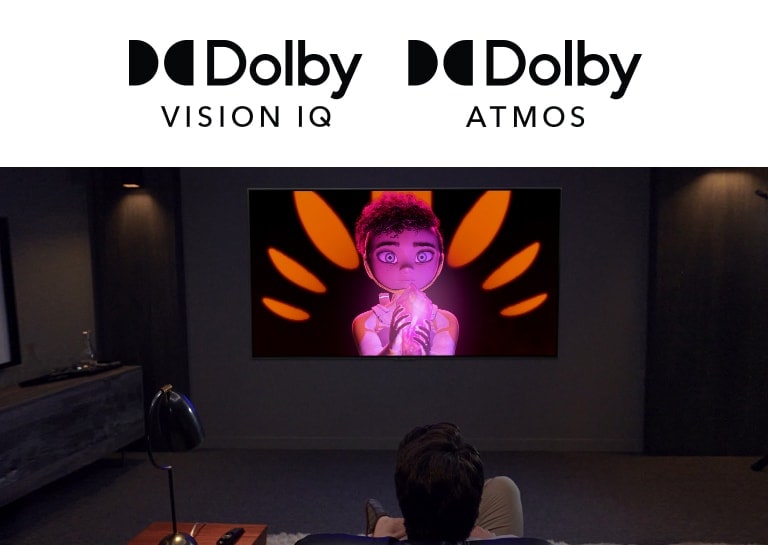 A man and boy sat side-by-side on a sofa watching a movie on a large flatscreen TV. The screen shows an animated character against a black background.