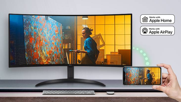 On the table, there is a monitor displaying a scene from a movie, and the same scene is displayed on a mobile device placed to the bottom right.