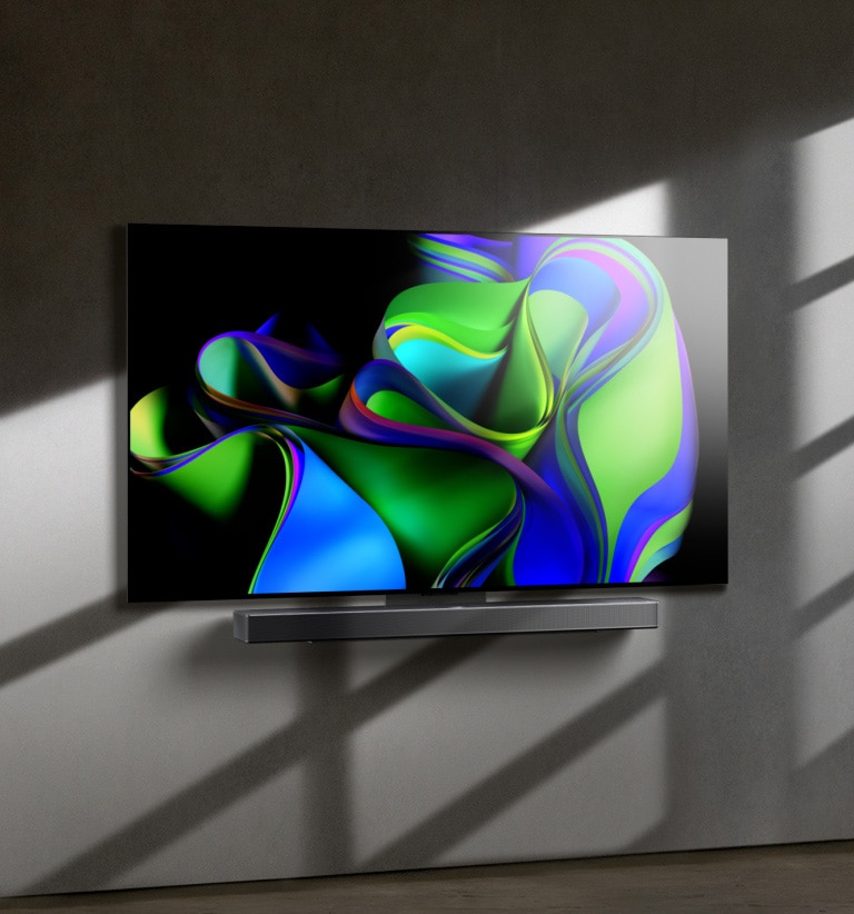 A video opens with the words LG OLED evo against a black background. The words enlargen and fill with color. Then the scene transitions to LG OLED C3, showing a colorful abstract artwork with a Soundbar against a white background. The white background becomes a wall in a room to which the TV attaches.