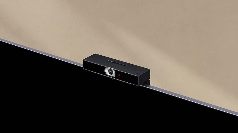 An image showing a close-up view of an LG Smart Cam installed on a TV in beige-colored space.