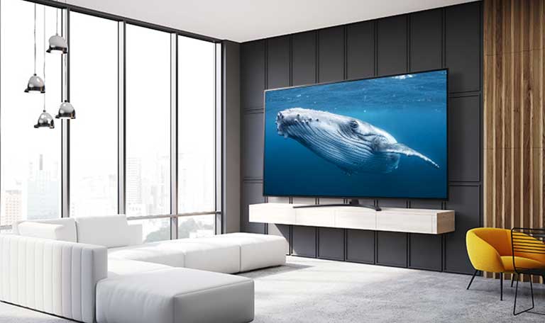 In a living room, there is a large screen TV displaying an image of a big whale in the sea.