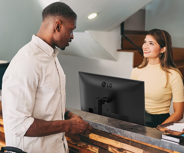A female receptionist is talking to a man at the front desk.	
