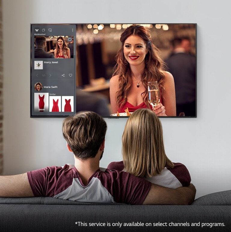 Couple sitting on a couch watching a TV displaying a woman and product information of a red dress the woman is wearing.
