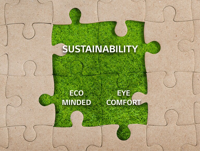 Four puzzle pieces in the middle of a kraft jigsaw puzzle are covered with a grass with texts of 'SUSTAINABILITY', 'ECO MINDED' and 'EYE COMFORT'.