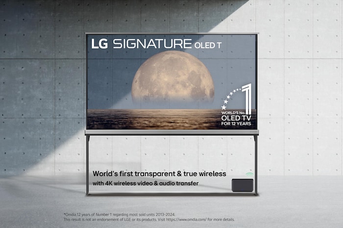 Vista frontale di LG SIGNATURE OLED T, 12 anni di emblema OLED numero 1 al mondo, logo LG SIGNATURE OLED T, entrambi integrati nello sfondo che raffigura la luna sopra la costa su uno schermo trasparente. La Zero Connect Box con trasferimento video e audio wireless 4K a 120Hz è collegata al TV e il segnale Wi-Fi in uscita dalla box.