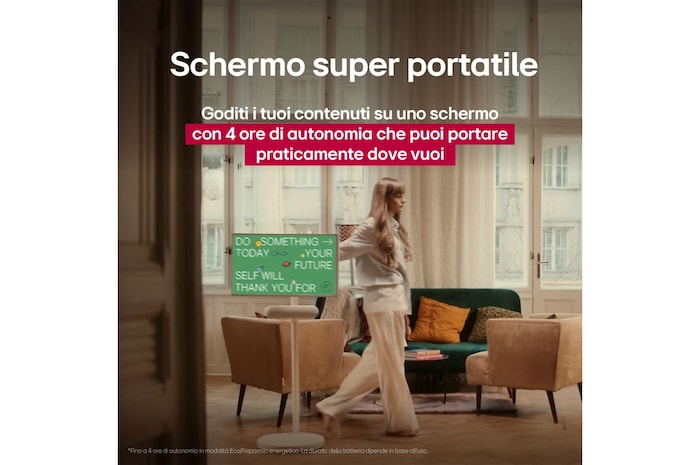 Persona che sposta il proprio LG StanbyME 2 grazie al supporto con ruote. Il testo evidenzia lo schermo super portatile con 4 ore di riproduzione wireless e porta USB-C.