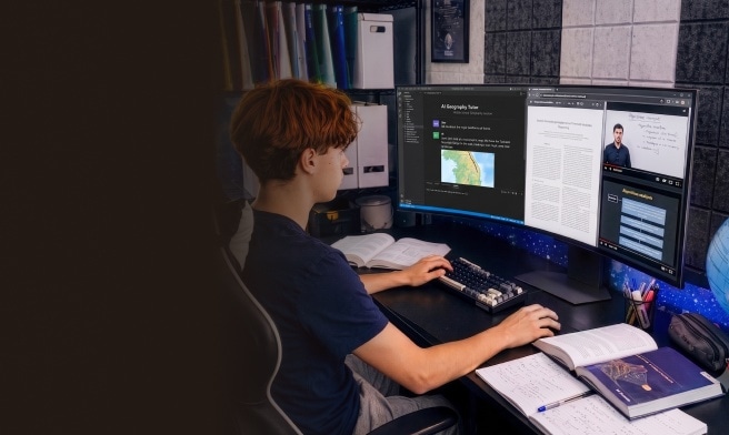 Uno studente lavora alla scrivania di casa utilizzando un setup con doppio monitor. Sullo schermo sono aperti materiali di studio, codice e contenuti didattici online, mentre libri e quaderni sono sparsi sul tavolo. L'ambiente appare organizzato e dedicato all'apprendimento e allo studio digitale.
