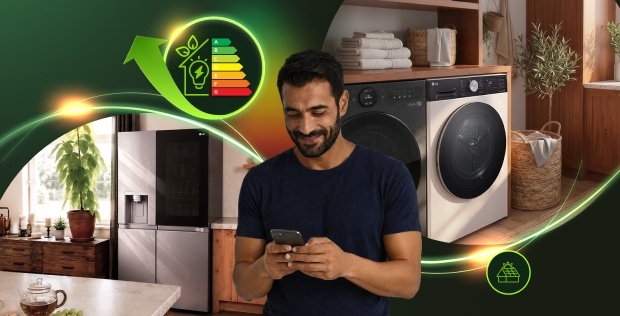 Uomo che usa uno smartphone in una moderna lavanderia con lavatrice, asciugatrice e frigorifero LG, circondato da grafiche luminose sull'efficienza energetica.