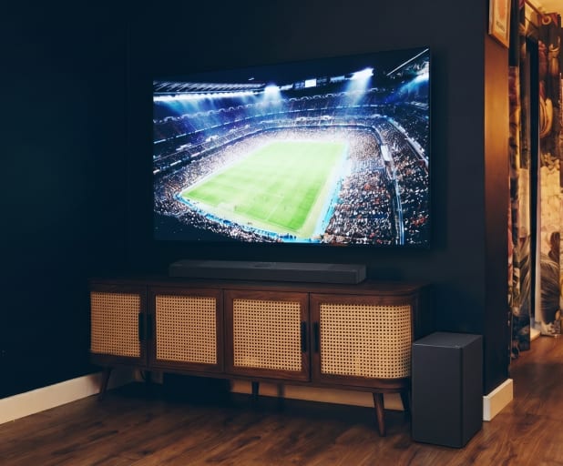 Primo piano di una soundbar sotto una TV su un mobile in legno